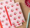 Pink notebook with cherry design on the cover.