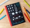 Notebook with space‑themed diagrams, including moon phases, planets, and a rocket on the cover.