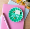 Green enamel flower-shaped trinket dish holding clips and small items
