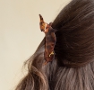 Hair claw clip featuring an adorable sausage dog design in translucent brown, with a marbled effect. 