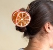 Hair claw clip featuring a fruity orange slice design, with hints of marbling and translucence. 