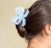 Hair claw clip featuring a pretty bow design in blue, with hints of marbling and translucence.