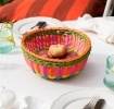 Round woven basket made of brightly coloured plastic.