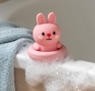 Pink silicone bunny bath toy with upright ears and simple face, in round base