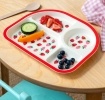 Strawberry-themed toddler divider plate shown with vegetables and fruits on a wooden table.