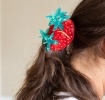 Hair claw clip featuring a sweet strawberry design in red, green and gold, with hints of marbling and translucence. 