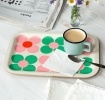 Wooden tray with pink and green daisy design, shown with a mug, spoon and napkin.