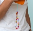 Colourful beaded phone strap attached to an orange phone, featuring heart beads and letter beads spelling “HAPPY”
