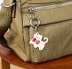 Cream cat-shaped keyring with red bow and silver ring attachment.