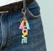 Gold keyring with colourful “LOVE” letter charm and pink and blue tassels.