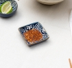 Square ceramic dipping bowl with a blue leaf pattern shown with chilli flakes.