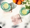 Set of two ceramic drinks coasters featuring an elegant embossed pattern, reminiscent of traditional tile designs.