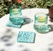 Turquoise ceramic tile coasters with white pattern beside two glasses of lemon water.