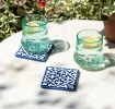Blue ceramic tile coasters with white pattern shown beside two glasses of lemon water.