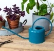 Blue metal watering can with curved handle and long spout.