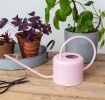 Pink metal watering can with curved handle and long spout.