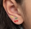 Stick-on earrings in cherry and lightning bolt shapes on a kid’s ear