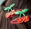 Pair of red glitter cherry hair clips with green glitter leaves