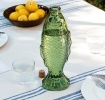 Green fish-shaped glass bottle with embossed scale pattern and cork stopper