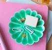 Green enamel flower-shaped trinket dish holding clips and small items