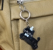 Black cat-shaped keyring with comb teeth, blue bow and hat attached to a silver ring.