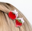 Set of two mini fruit-shaped hair claw clips in strawberry and apple designs.