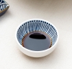 Round ceramic dipping bowl with blue line pattern shown with soy sauce.
