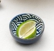 Round ceramic dipping bowl with blue wave pattern shown with lime wedges.
