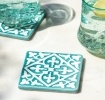 Turquoise ceramic tile coasters with white pattern beside two glasses of lemon water.