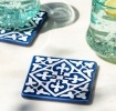 Blue ceramic tile coasters with white pattern shown beside two glasses of lemon water.