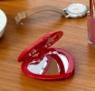 Red heart-shaped compact mirror on a wooden surface