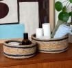 Set of two round woven storage baskets with black stripe detail.