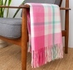 Check pattern in pink, white and teal blanket displayed over a wooden armchair