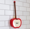 Red apple-shaped toilet brush and holder with wall mount, displayed against white tiled wall.