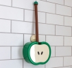 Green apple-shaped toilet brush and holder with wall mount, displayed against white tiled wall.