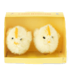Two fluffy yellow chick decorations sitting side by side inside a small yellow cardboard box