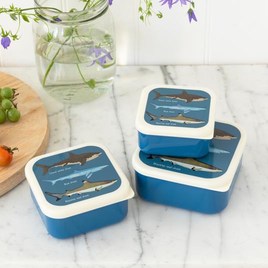 Three plastic snack boxes in dark blue and cream featuring pictures of sharks