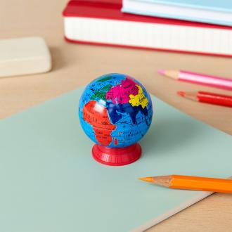 Colourful globe sharpener with a red base placed on a notebook 