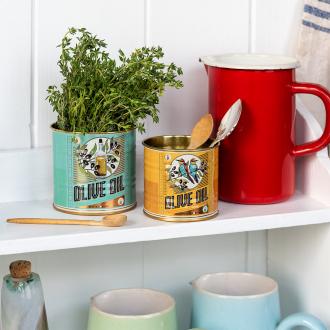 Two olive oil tins repurposed as herb and utensil holders on a kitchen shelf.