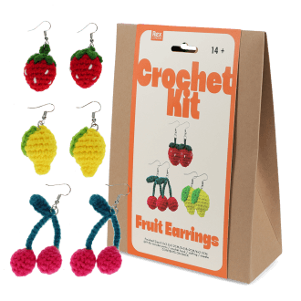 Crochet kit packaging placed beside three finished crocheted earrings shaped like strawberries, lemons, and cherries