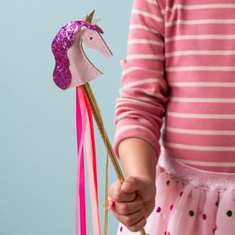 Kid holding pink unicorn wand with glittery top and ribbon streamers