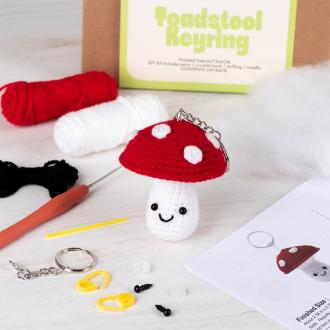 Crochet kit packaging displayed next to a finished red and white toadstool mushroom keychain