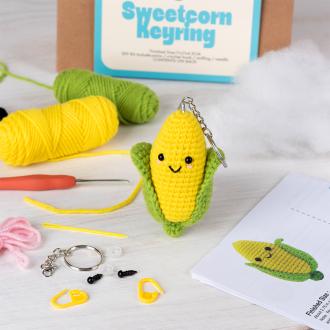 Crochet kit packaging displayed next to a finished yellow and green leaf sweetcorn keychain