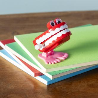 Wind-up toy shaped like red chattering teeth with white teeth, googly eyes, and pink feet