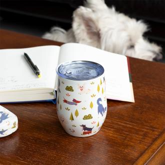 Travel cup with playful dog illustrations on a wooden table.