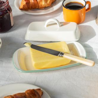 Rectangular white enamel butter dish with a pistachio green rim and a handled lid displayed with butter.