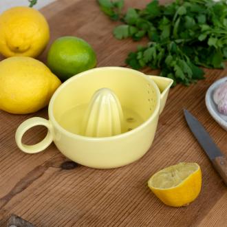 A yellow ceramic lemon juicer shown with sliced lemons.