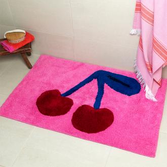 A pink tufted bath mat featuring a cherry motif.