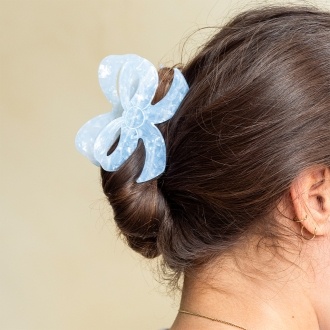 Hair claw clip featuring a pretty bow design in blue, with hints of marbling and translucence.