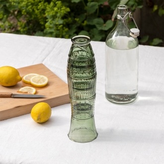 Stacked green glass tumblers placed beside a bottle of water